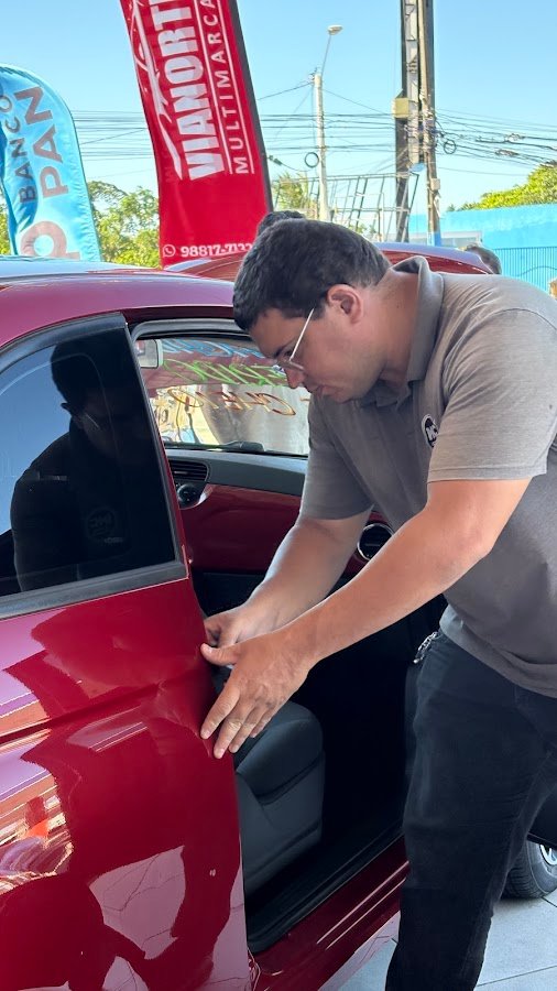 Inspetor verificando a porta de um carro vermelho